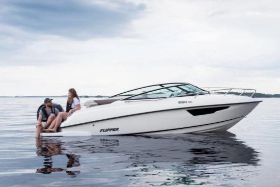 A couple relaxes on a white Flipper boat on calm waters under a cloudy sky, showcasing leisure and boating enjoyment.